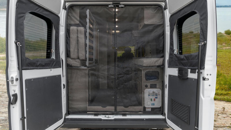 Rear view of an RV rental with open doors and a bug screen, revealing a cozy interior setup, parked by a lake. — photo 12