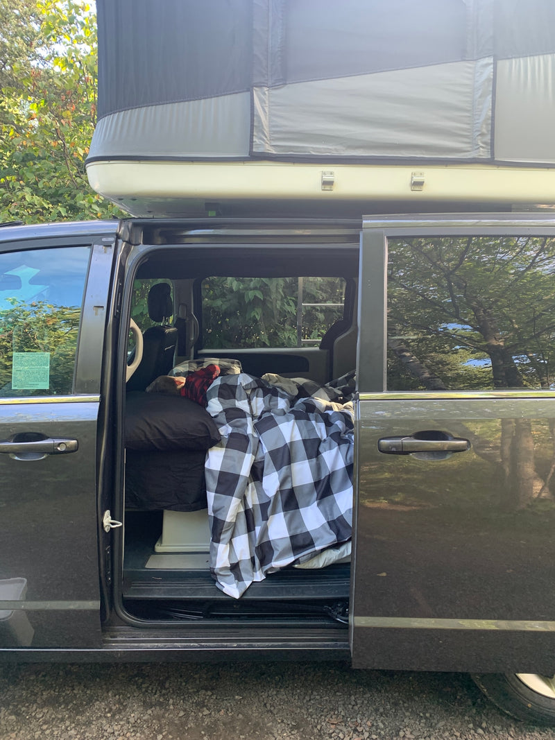 perfect for an RV rental. Blue mattress laid over folded seats creates a comfy sleeping area.|This customized minivan — photo 8