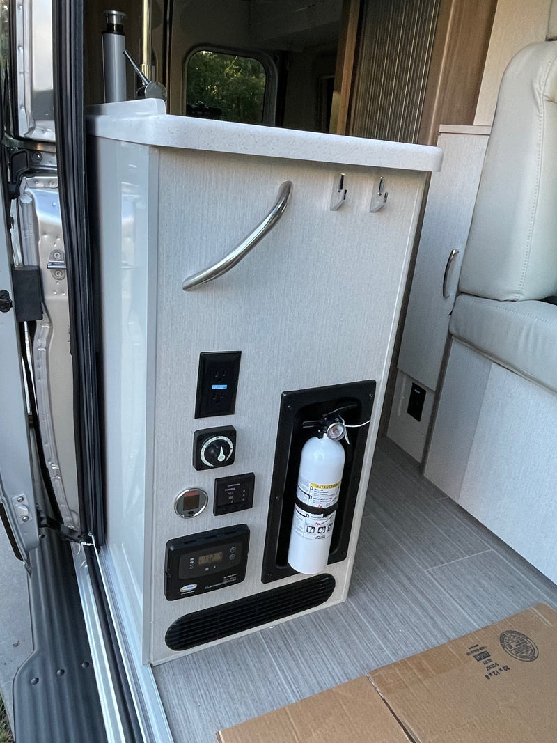 RV rental interior featuring a control panel with various gauges & switches, plus a readily accessible fire extinguisher. — photo 9