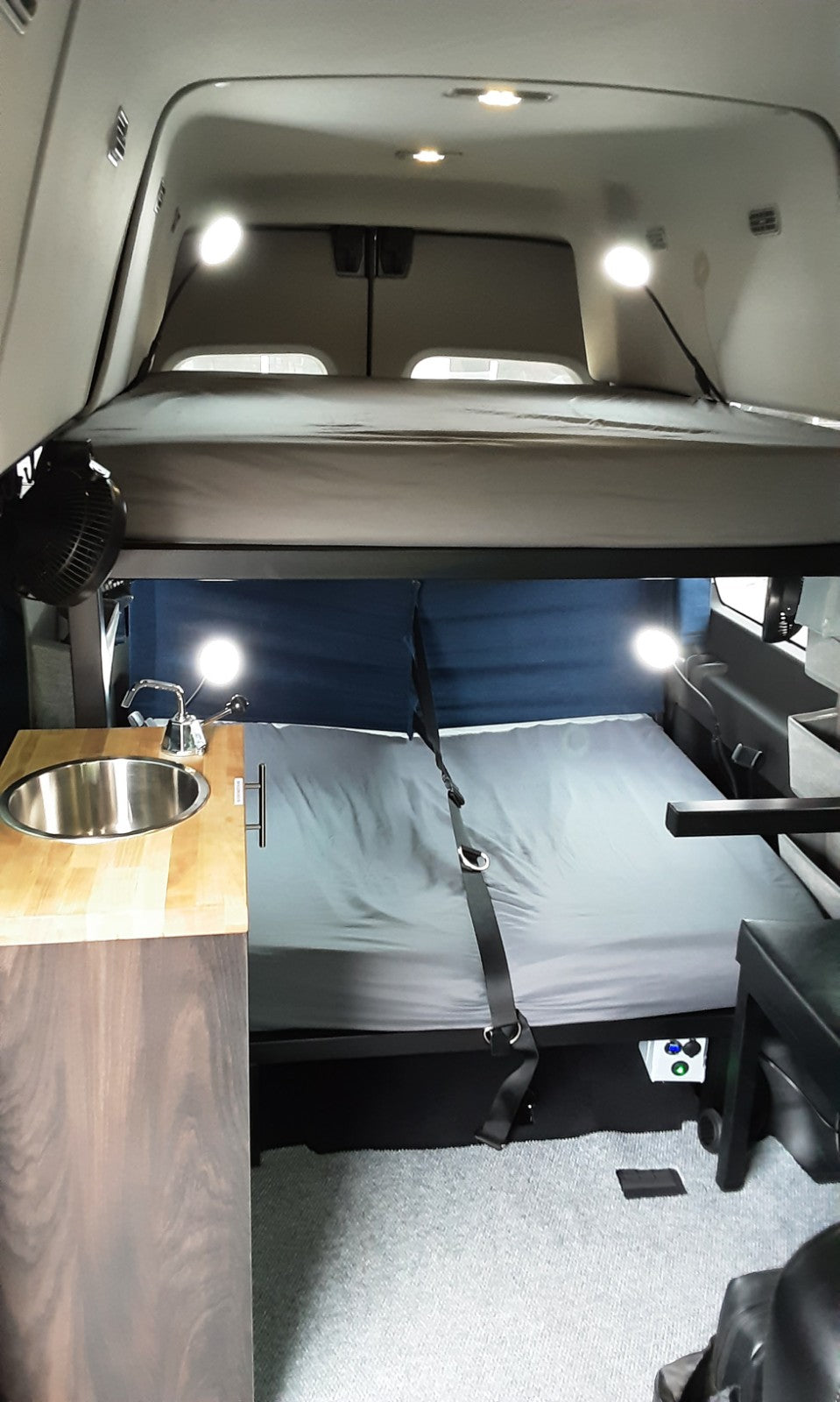 RV rental interior: cozy camper van with bunk beds, sink, and built-in amenities for travel.