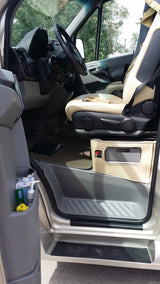 RV rental interior view: driver's cockpit, beige passenger seat, door storage with sanitizer, and a custom base unit.
