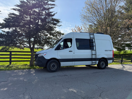 Experience nature with this Geotrek rv rental! White adventure van parked by a serene horse farm & green fields.