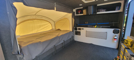 This rv rental features a comfy pop-up bed, shelving, a TV, and storage inside its compact, carpeted interior.