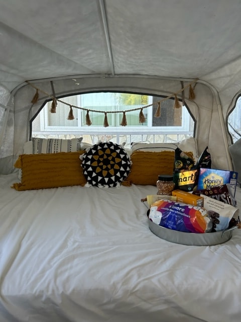 Experience a luxurious RV rental stay! This cozy interior features a plush bed, stylish pillows, and a tray of delicious s'mores. — photo 8