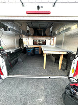 Truck bed converted to an RV rental-ready camper. Features wood bed platforms, insulated walls, and storage for overlanding trips.