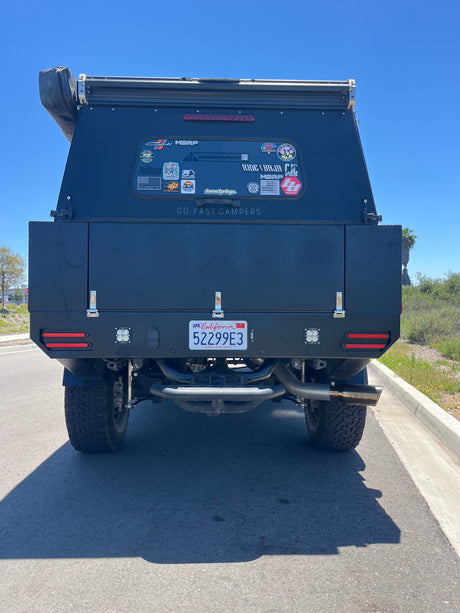 Back of a black "Go Fast Campers" overlanding rig, featuring custom lights. An ideal rv rental for your next outdoor adventure.