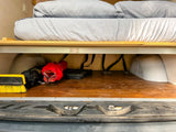 Compact RV rental interior: elevated bed with spacious under-bed storage for gear like brushes & bags.
