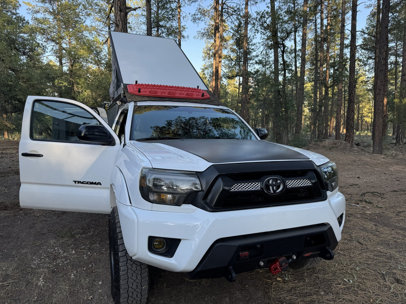 White Toyota Tacoma with open rooftop tent, red traction boards, & off-road gear. Great for an RV rental adventure! — photo 11