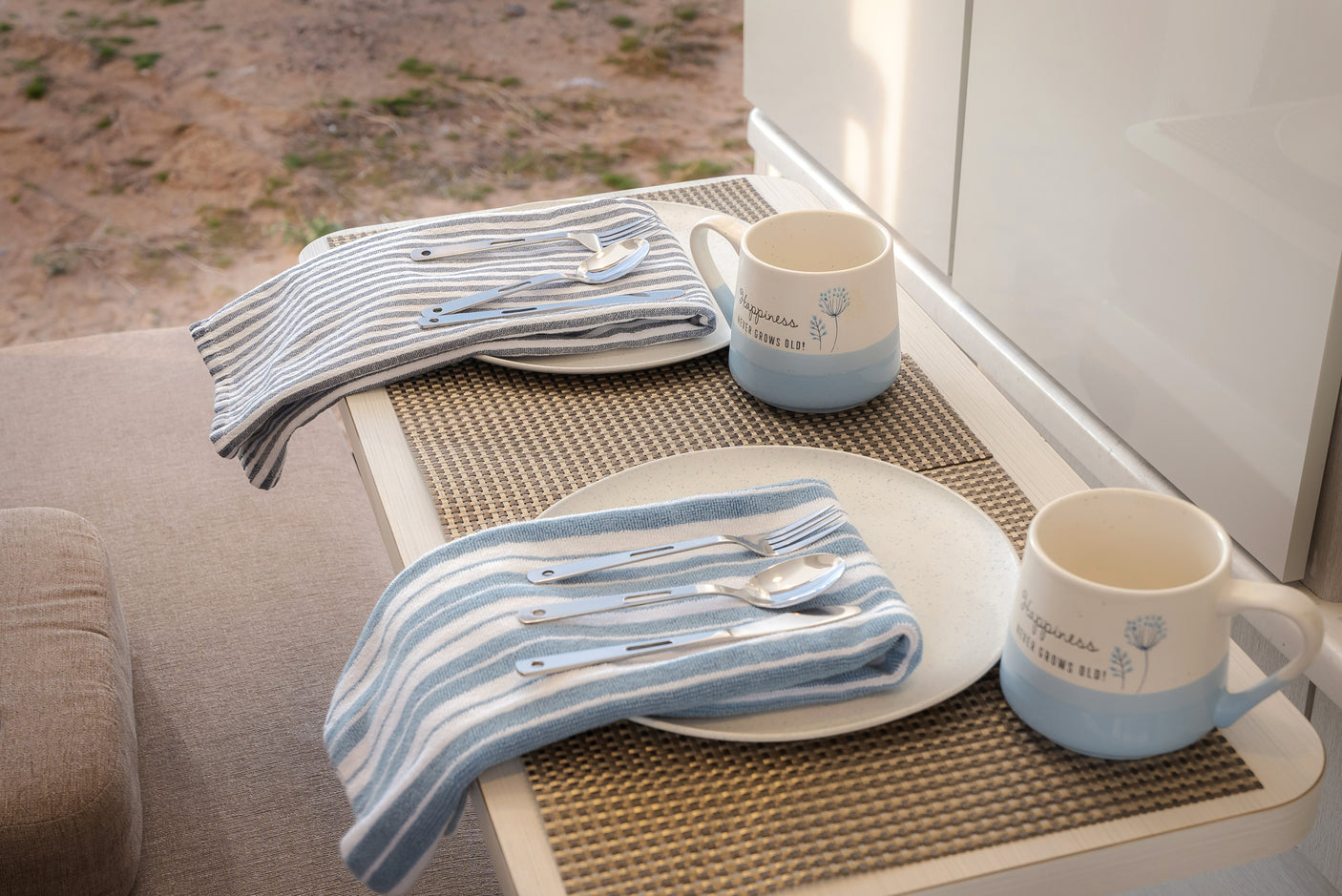 RV rental comfort: Two complete place settings with blue-striped napkins and mugs await your next on-the-go meal.