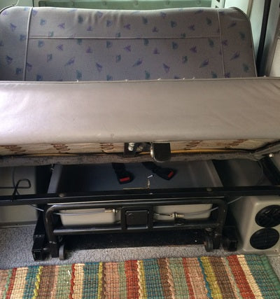 RV rental interior: Rear bench seat converts to bed, revealing under-seat storage, water tanks & a heater for comfortable travel.