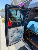 RV rental camper van with open door, showing a custom pebble panel, outdoor shower setup, and LiFePO4 battery.