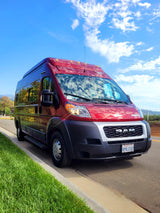 Stylish red Ram ProMaster RV rental parked curbside on a sunny day. Ready for adventure!