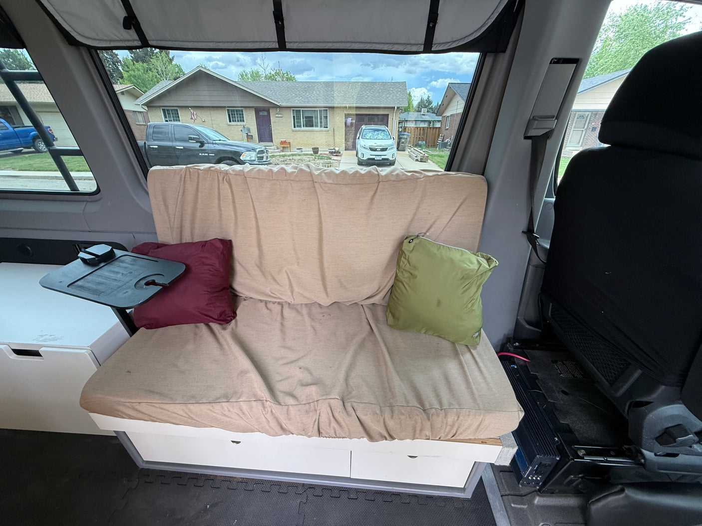 Cozy RV rental interior with bench seating, clever storage, and a view of a suburban street. Perfect for your next adventure!