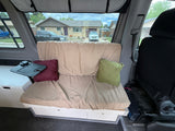 Cozy RV rental interior with bench seating, clever storage, and a view of a suburban street. Perfect for your next adventure!