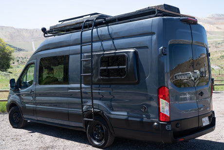 Dark gray Ford Transit camper van, customized for adventure, shown from the rear-side view, ideal for an rv rental experience.