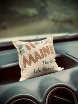 A small 'Maine' souvenir pillow with pinecones rests in an RV rental dashboard, ready for adventure.