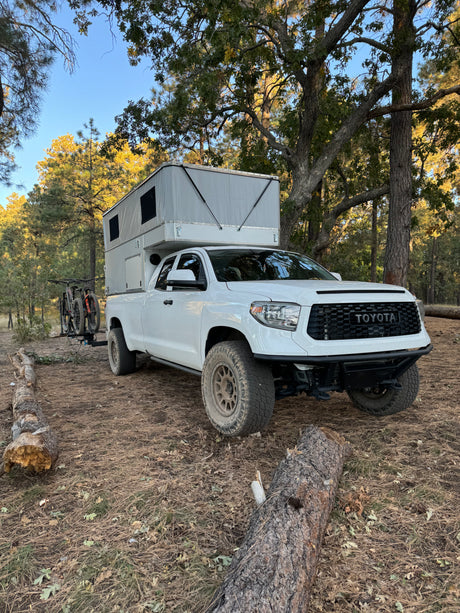 White Toyota Tundra with a pop-up RV camper and bikes, ready for an RV rental adventure.
