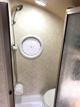 RV rental bathroom: Efficient space with a shower, toilet, and distinctive circular window, optimized for compact living.