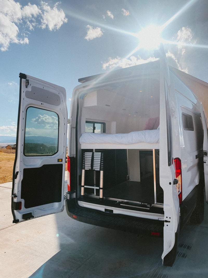 Explore our RV rental camper van's interior! Rear doors open to reveal a comfy bed, storage, and ladder, perfect for sunny day travel. — photo 10
