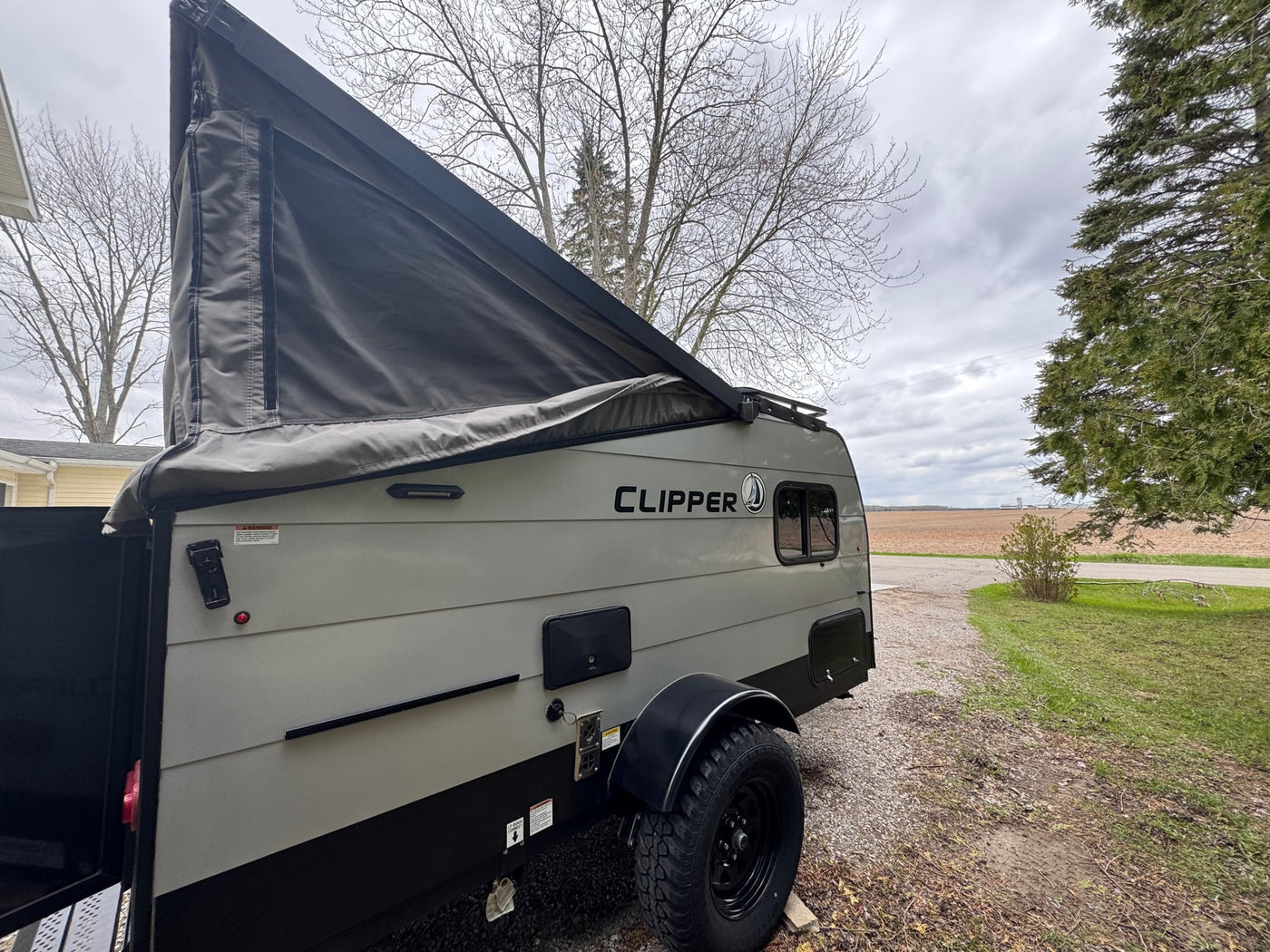  and hitch.|Grey pop-up RV rental with 'Clipper' branding and partially extended canvas roof for travel adventures.|RV rental power inlet. Side view of a black electrical inlet with three metal prongs (two flat — photo 7