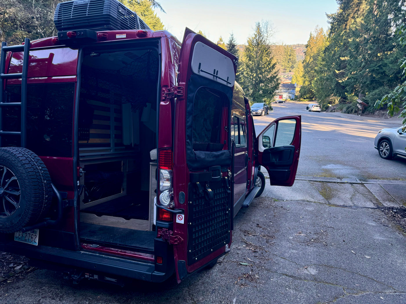 This burgundy camper van, equipped with roof AC and bed, features open doors, suggesting an rv rental ready for adventure. — photo 4