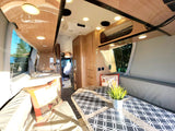 Step inside this inviting RV rental: a well-appointed interior with kitchenette, dining space, comfortable seating, and a clear lake view.