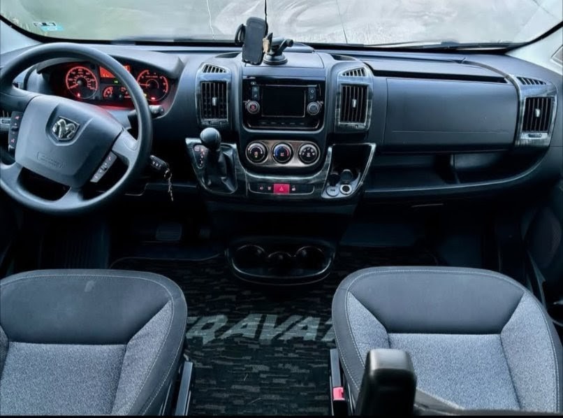 Inside an RV rental: a modern cockpit with steering wheel, dashboard, infotainment, and comfortable front seats.