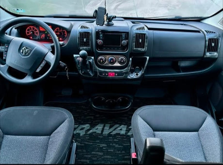 Inside an RV rental: a modern cockpit with steering wheel, dashboard, infotainment, and comfortable front seats.