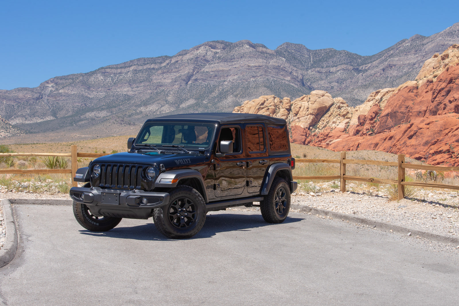 A black Jeep Wrangler in a desert landscape with red rocks, perfect for exploring adventure destinations often sought by RV rental travelers.