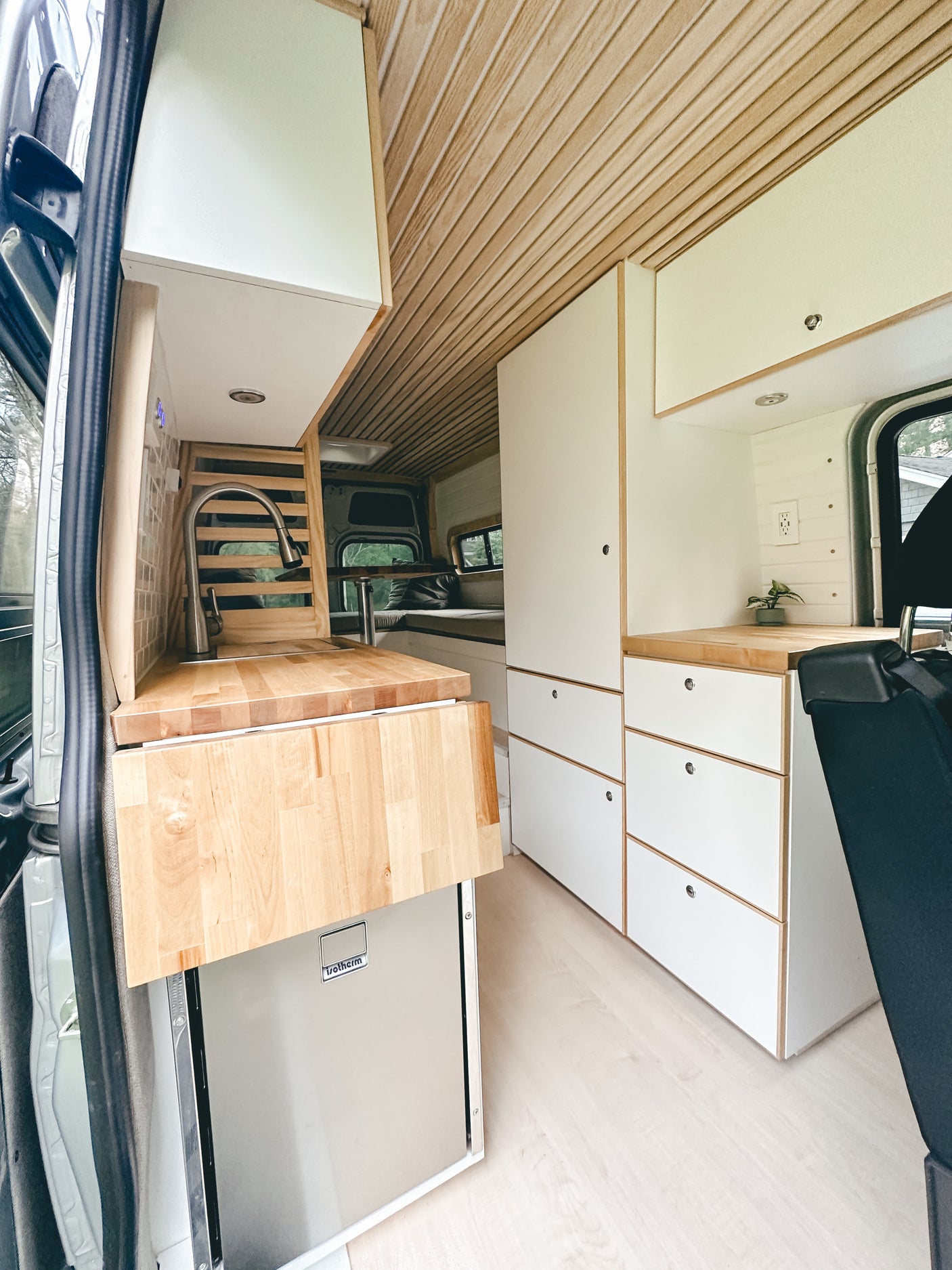 Spacious RV rental interior featuring a functional camper kitchen, wood ceiling, and ample storage for comfortable mobile living.