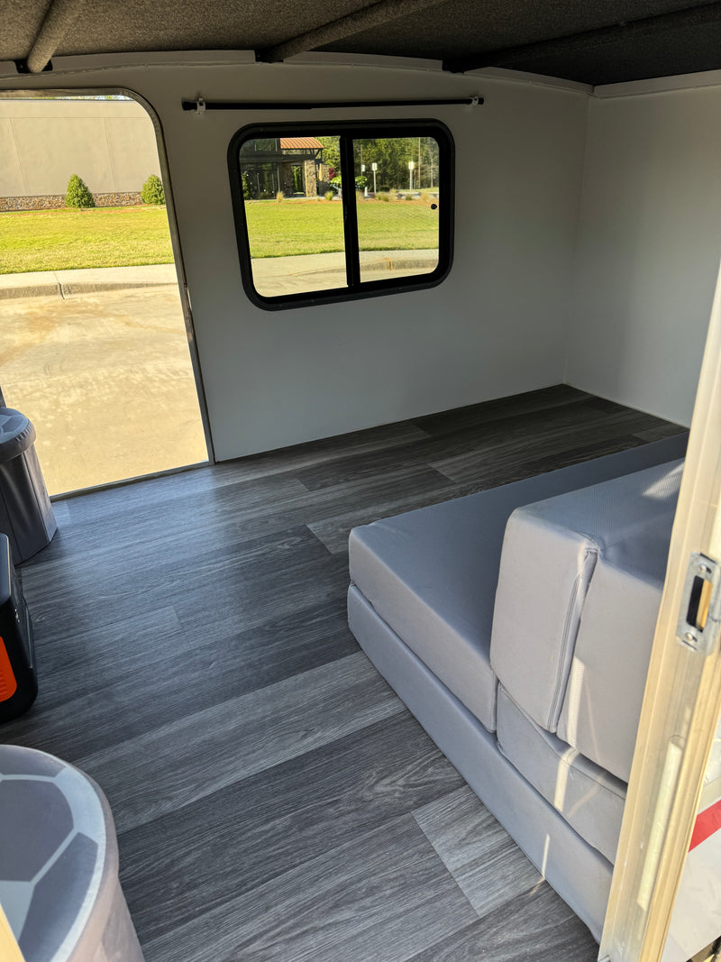 Clean RV rental interior with grey flooring, window view, and foldable bed. Ideal for compact travel. — photo 8