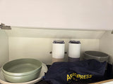 Organized RV rental kitchen cabinet featuring an Aeropress, travel mugs, and stackable bowls.