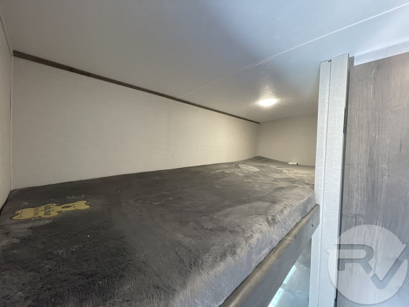 Cozy RV rental bunk bed interior, featuring a plush grey mattress, overhead light, and Safety Bear sticker. — photo 14
