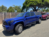 A blue Toyota Tacoma pickup with bed cap & red RAV4 parked. Adventure awaits! Look into rv rental options.