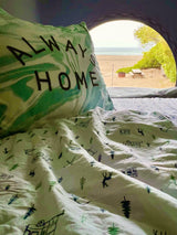Cozy rv rental bed with "ALWAYS HOME" pillow offers a serene beach and ocean view from inside. Perfect nature escape.