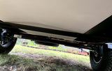 View of an RV rental's rugged underside: heavy-duty chassis, axle, off-road tires, and spare tire storage.