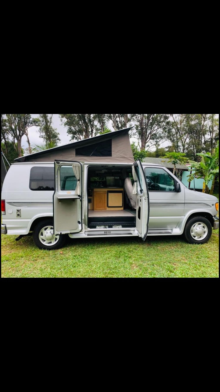 Silver pop-top camper van parked on grass with its side door open, revealing a compact interior for RV rental. — photo 7