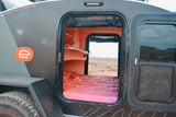 Step inside this compact RV rental! See the cozy bed, built-in shelves, and the desert landscape outside.