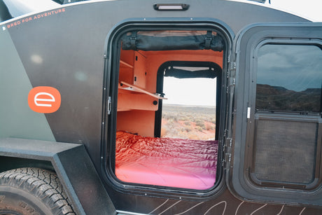 Step inside this compact RV rental! See the cozy bed, built-in shelves, and the desert landscape outside.