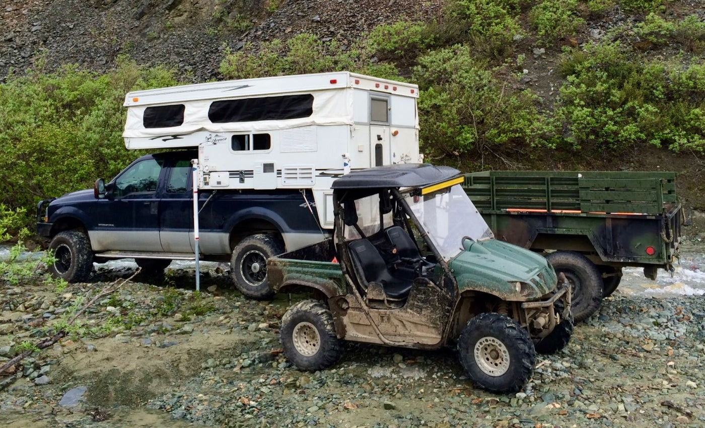  mountains under blue sky. Perfect for an outdoor RV rental road trip.|Mud-splattered RV rental parked in vast green tundra under a cloudy sky — photo 14