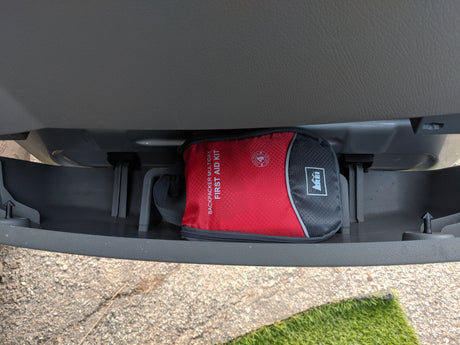 A red REI Backpacker First Aid Kit in an RV rental storage bin, essential for safety on road trips.