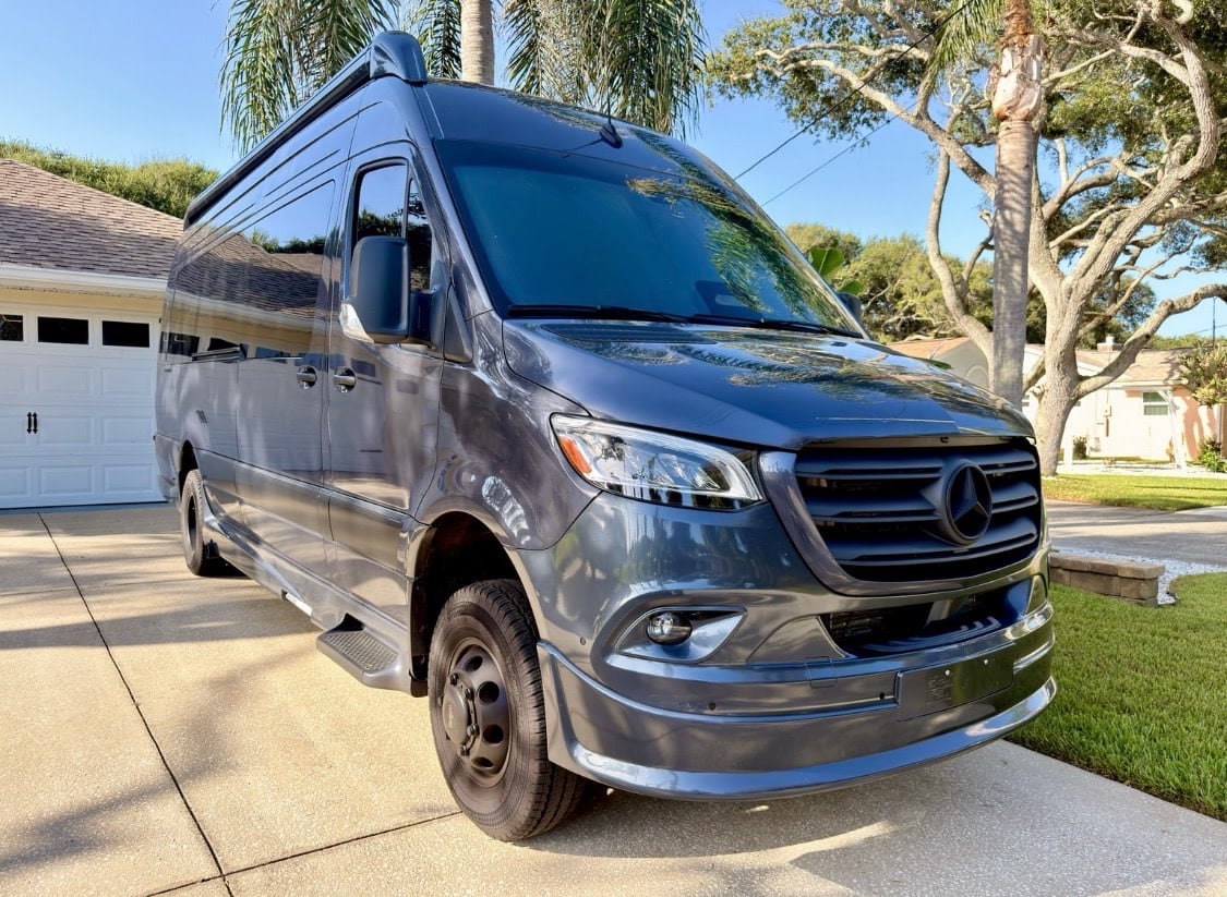 Dark gray Mercedes Sprinter RV rental van parked on a sunny driveway. Perfect for your next adventure.|Spacious RV rental interior featuring comfortable gray seating