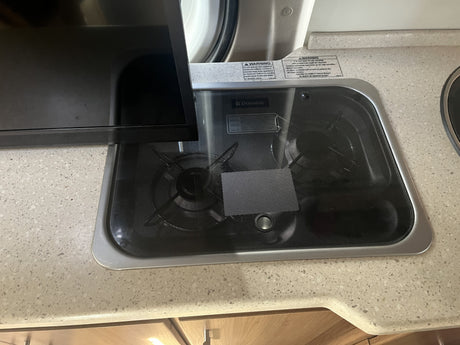RV rental kitchen: Dometic two-burner cooktop with cover and warning labels on a light-colored counter.