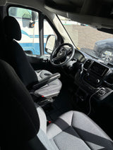 Inside a comfortable rv rental van, featuring the driver's cockpit, dashboard, and infotainment system, with an RV nearby.