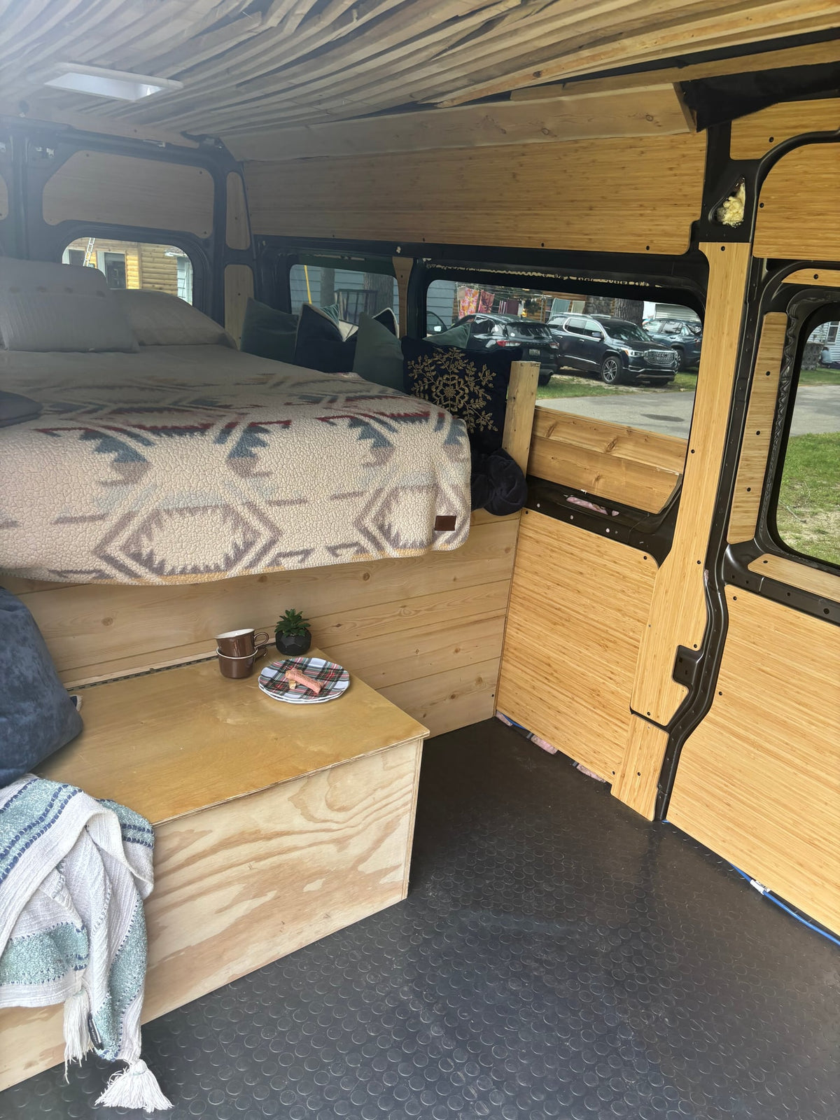  flanked by grass and tall trees. A boat is visible nearby in the sun.|Interior of an RV rental camper van — photo 2