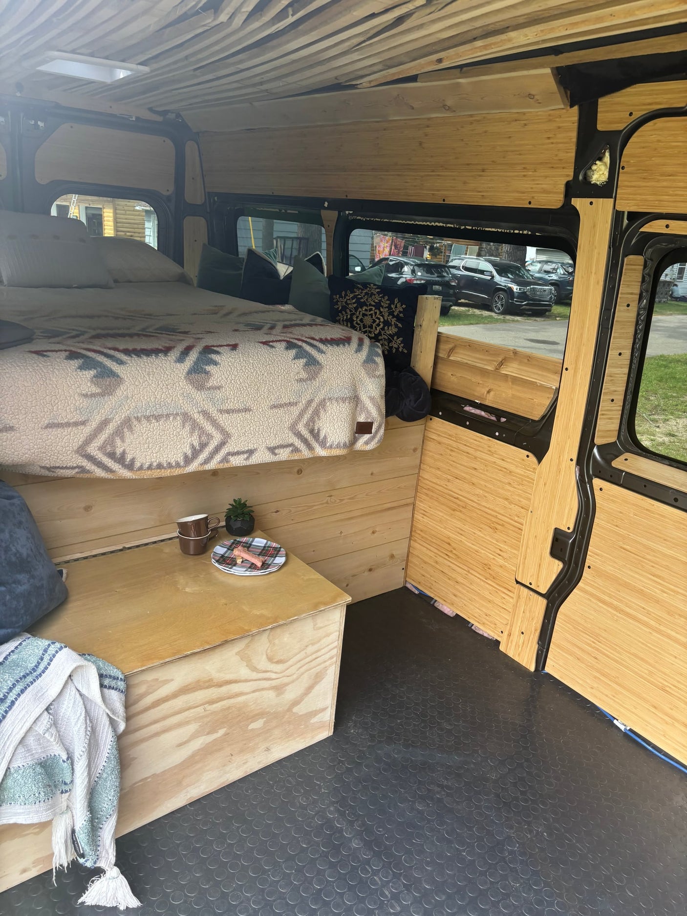  flanked by grass and tall trees. A boat is visible nearby in the sun.|Interior of an RV rental camper van