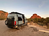 Adventure awaits! This grey RV rental camper van is parked amidst Sedona's stunning red rocks with a dog on board.