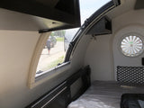 This compact rv rental interior features a comfortable bed, large side window, and distinct circular rear window.