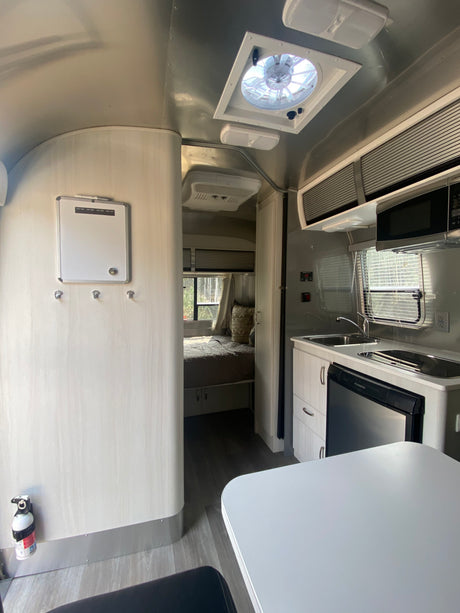 Modern Airstream RV rental interior features a kitchen, bedroom, and dining area, ready for adventure.
