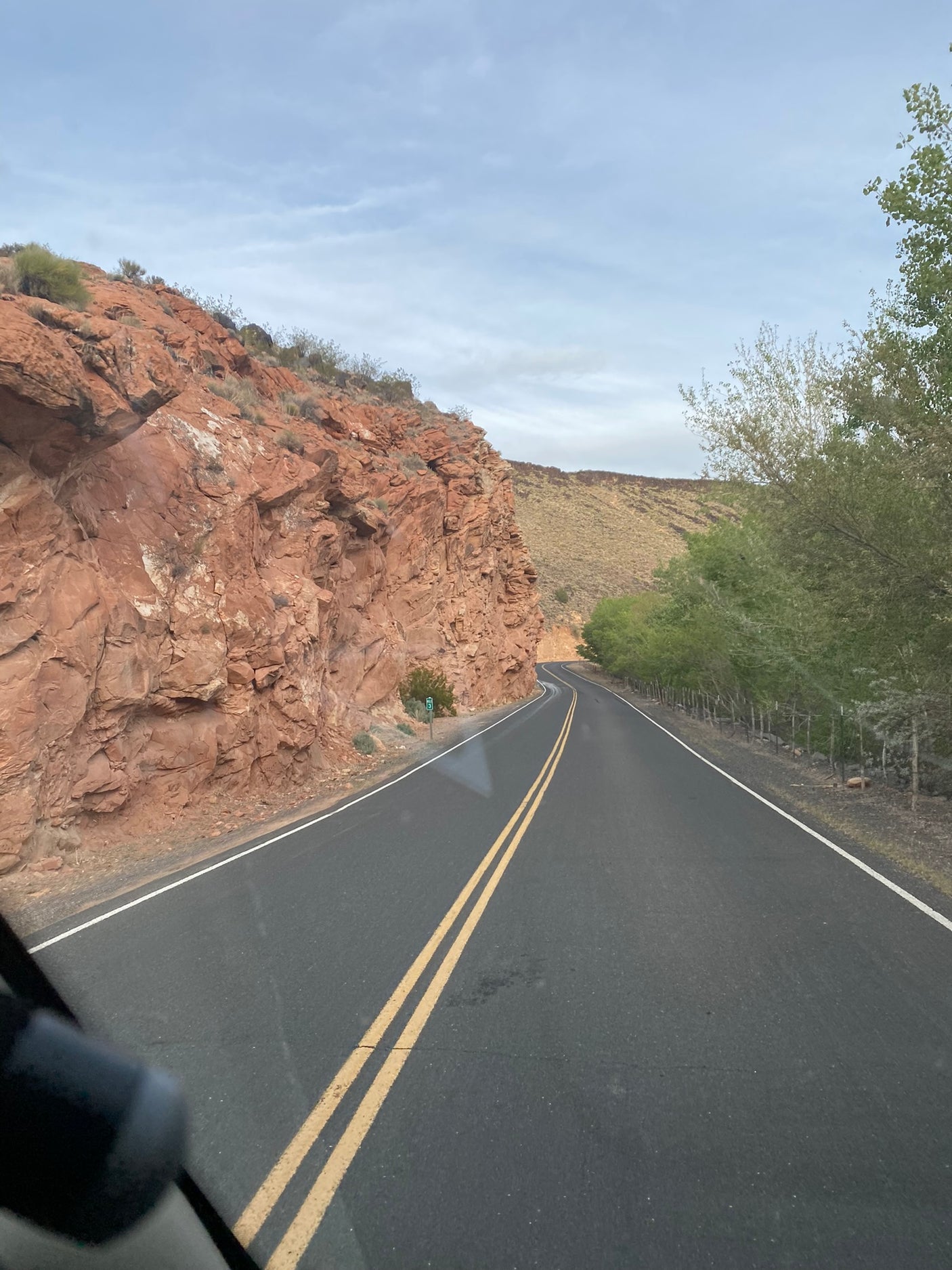 Winding road through red rock cliffs and green trees, ideal for an RV rental journey.
